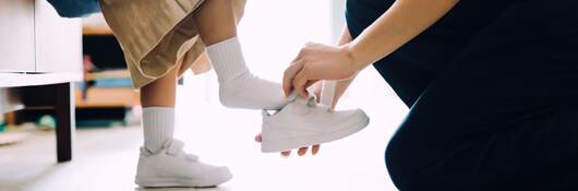 Mother putting on shoes for her daughter.